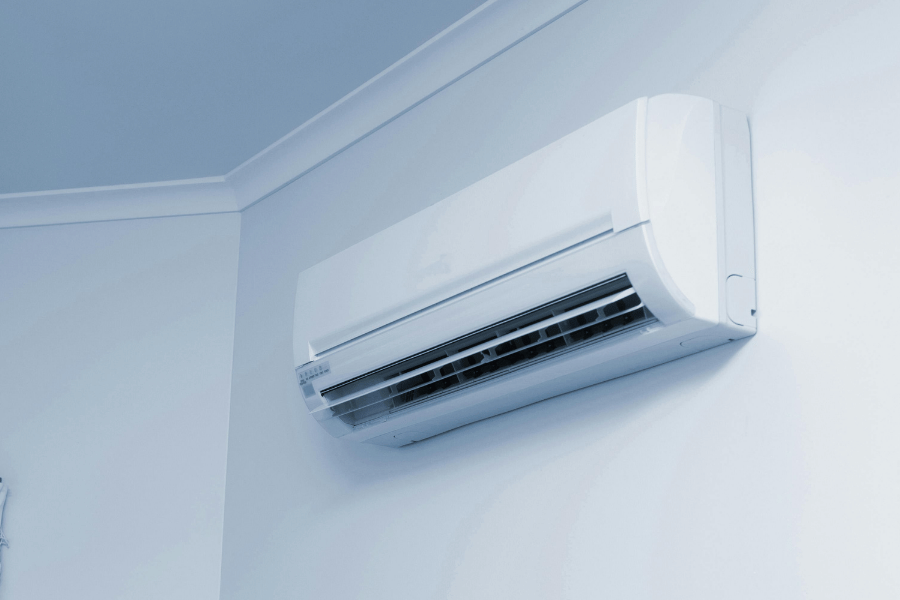 White wall-mounted air conditioner unit near the ceiling, cooling the room.
