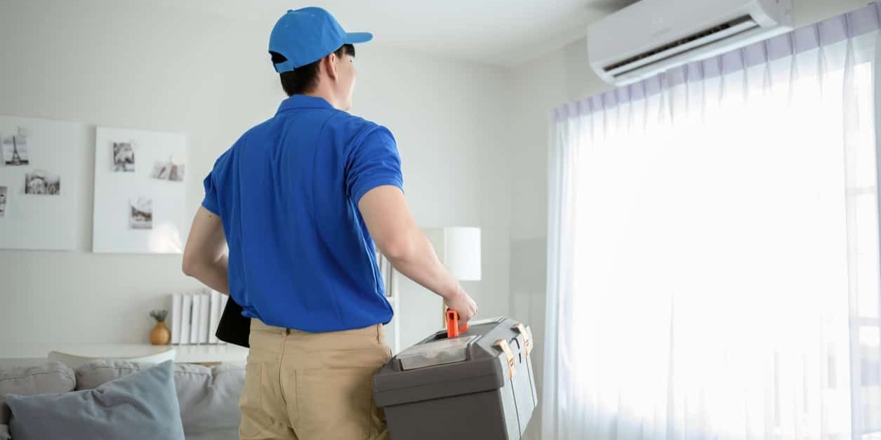 An Asian young Technician service man wearing blue uniform checking ,  cleaning air conditioner in home
