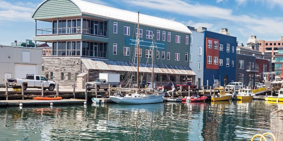 Colorful waterfront buildings along a harbor with boats and calm water reflecting the sky.